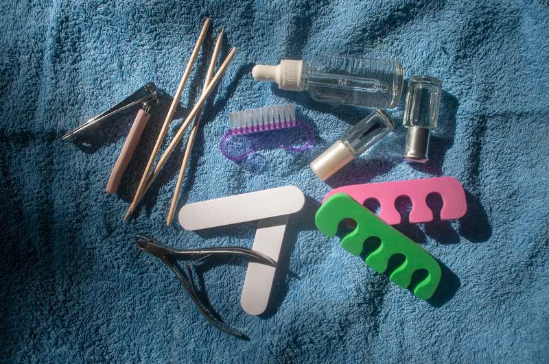 Blogger using fine-tip nail brushes and stamping plates at a well-lit vanity