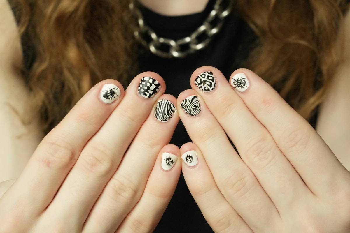 Close-up of hand applying nail art embellishment with tweezers and UV gel glue